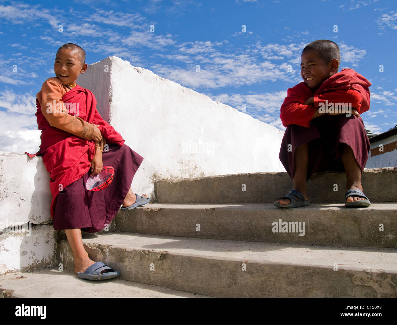 Young smiling monks sitting in front of a temple. Stock Photo