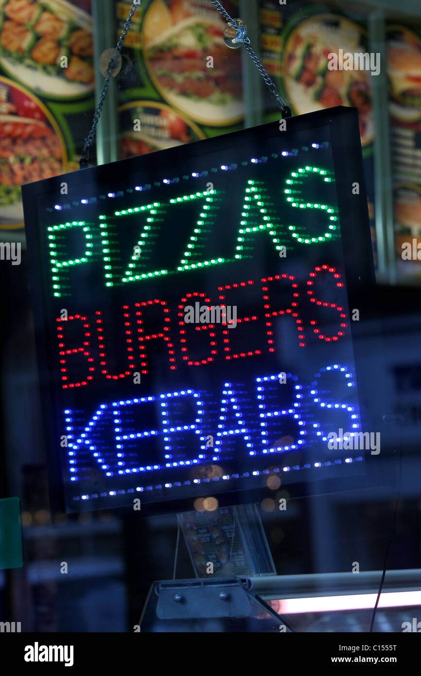 Take-away pizzas, burgers, kebabs sign and logo in a shop window in Hove, East Sussex, UK. Stock Photo