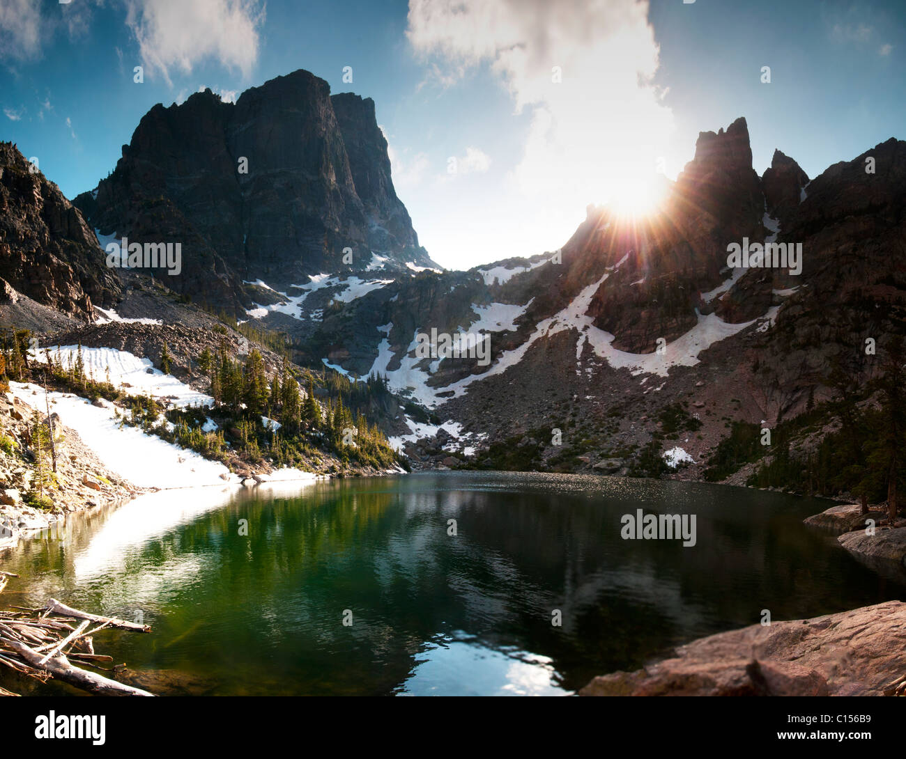 The sun rises over a lake in the high mountains of Rocky Mountain National Park Stock Photo