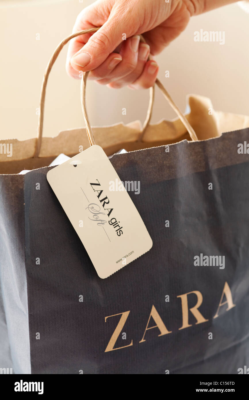 Female hand holding Zara shopping bag full of clothes Stock Photo - Alamy