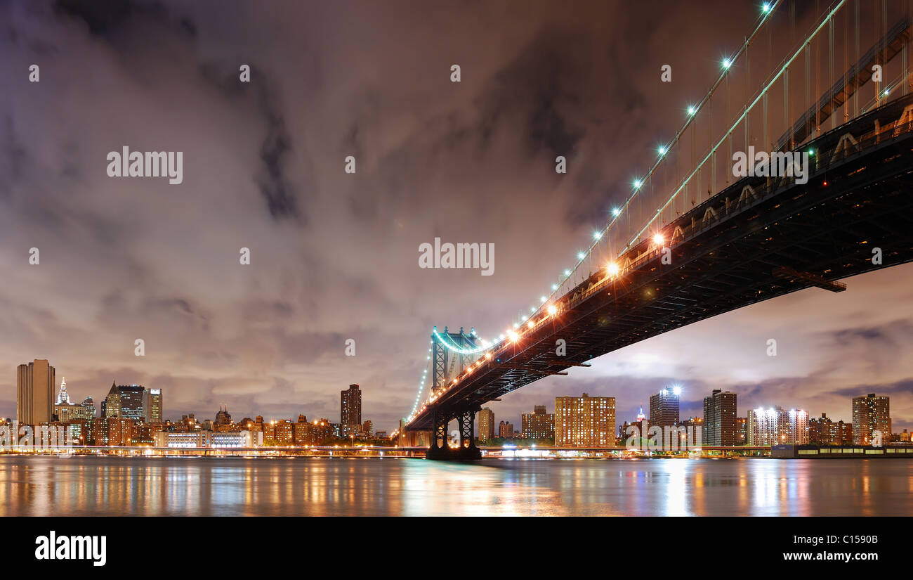 New York City Manhattan Bridge with city skyline at night illuminated over East River. Stock Photo