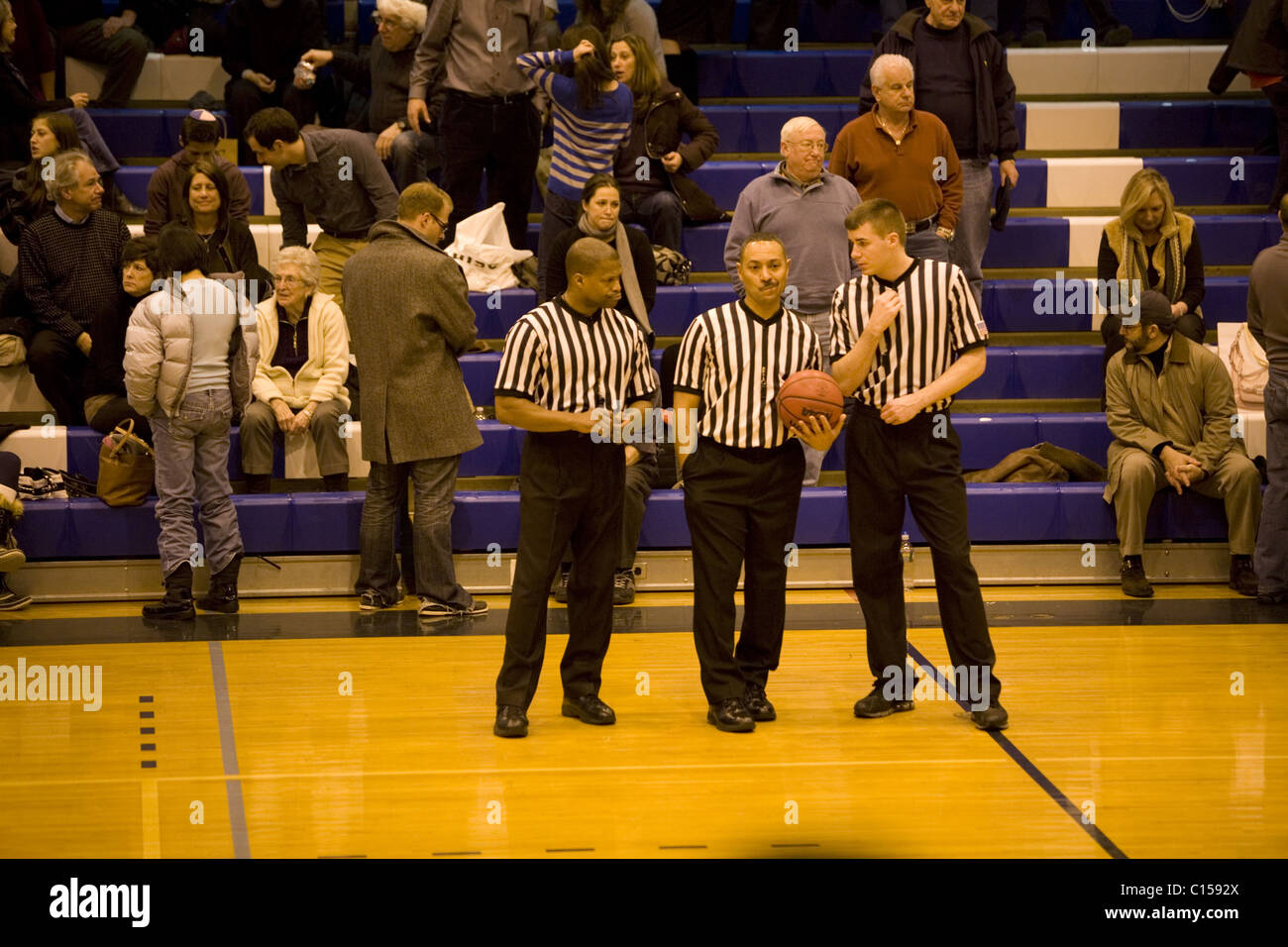 Referees consult at half time at a college basketball game in New York City. Stock Photo