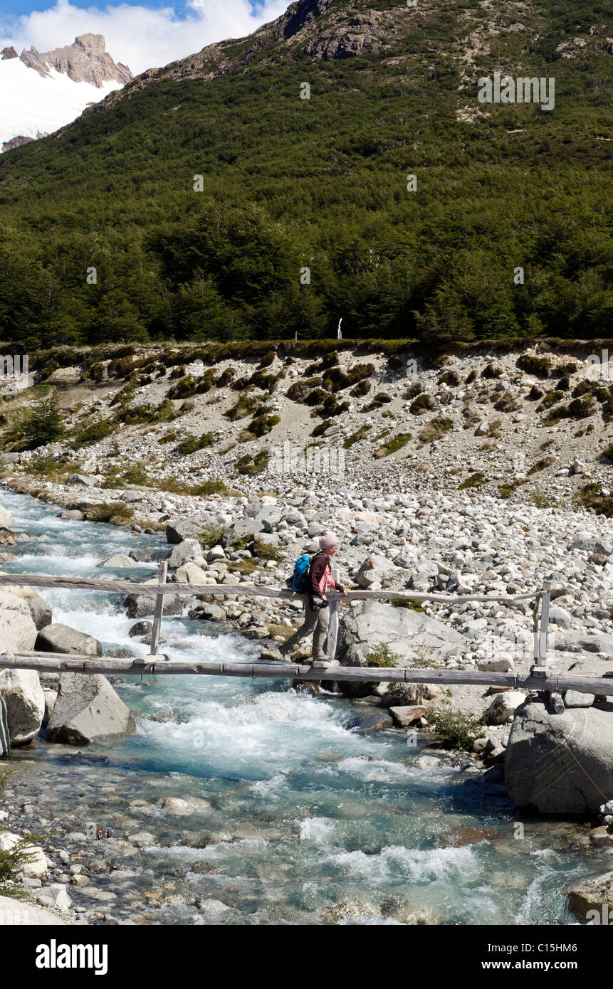 Woman crossing a bridge in the direction of Fitz Roy, Patagonia, Argentina Stock Photo