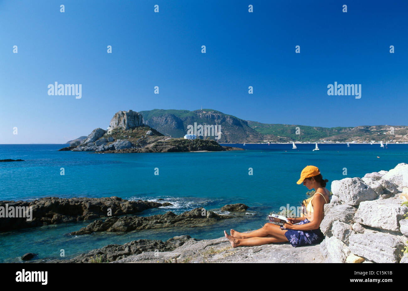Woman reading by the sea, Agios Stefanos, Kos, Dodecanese Islands, Greece Stock Photo