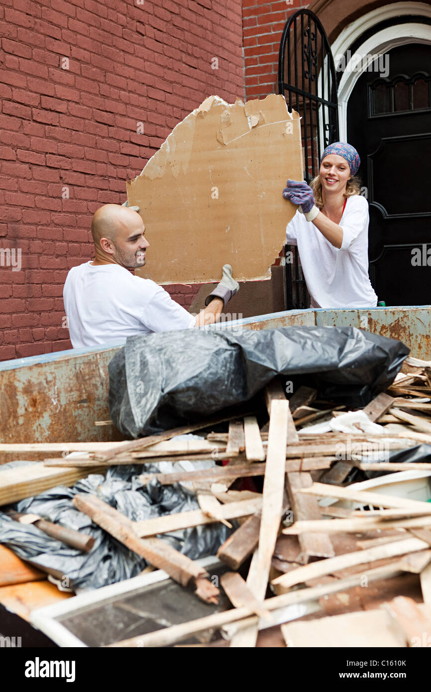 Couple filling skip with rubble Stock Photo Alamy