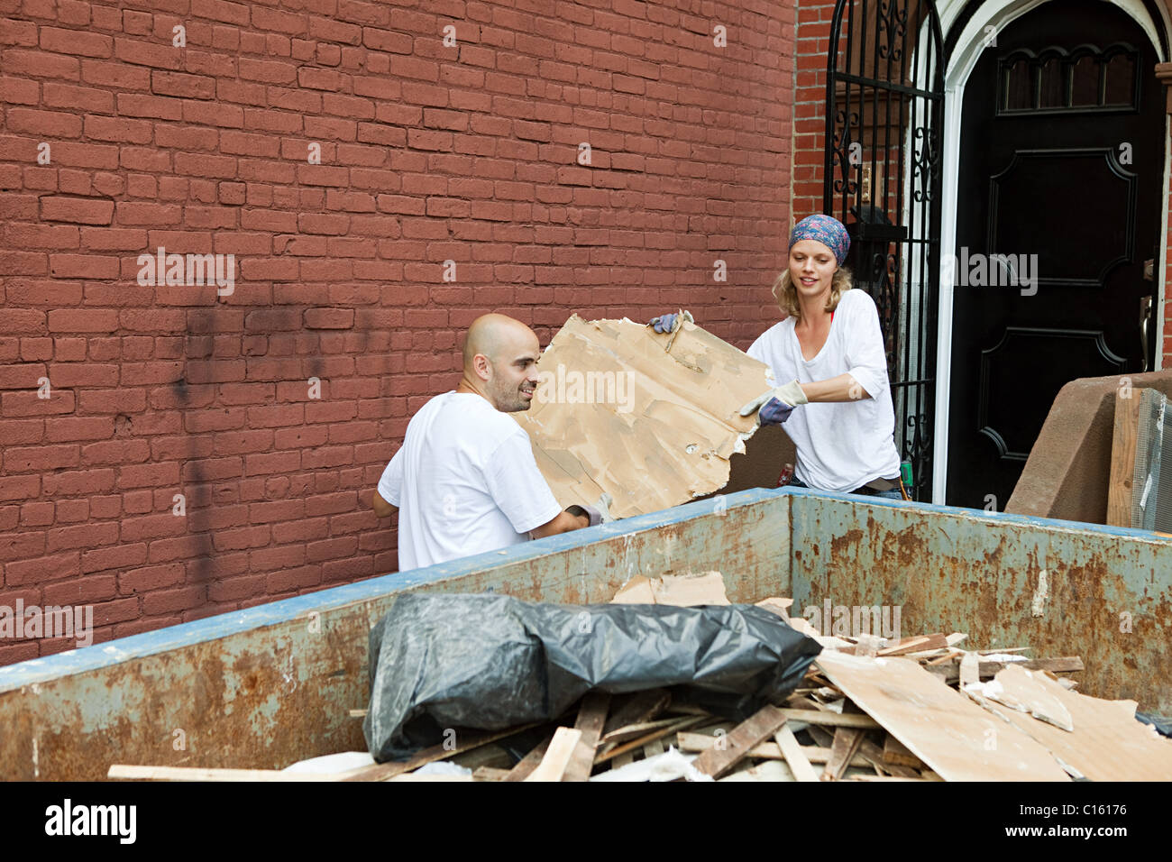 Couple filling skip with rubble Stock Photo Alamy