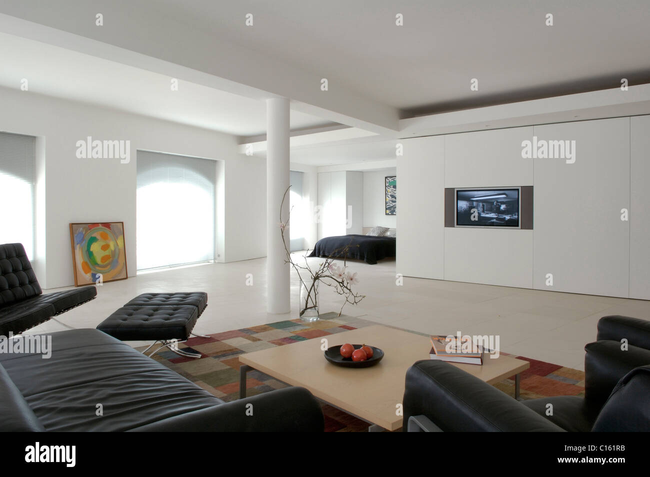 Living room in converted warehouse with black barcelona chair and coffee table Stock Photo