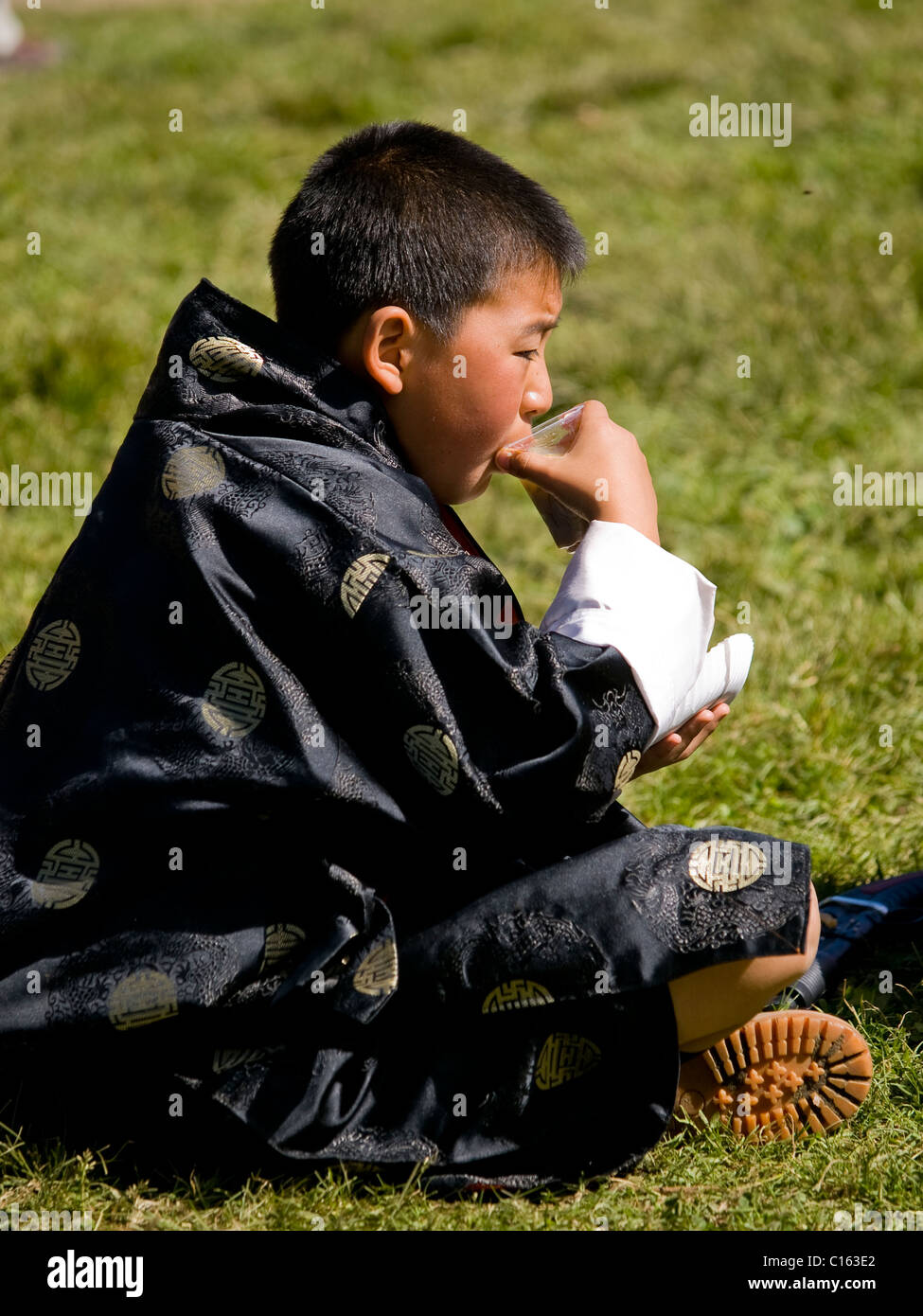Young boy in a traditional gho drinking Stock Photo