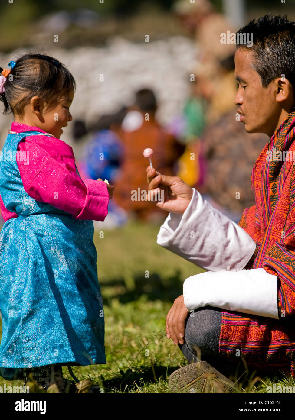 Young girl in a traditional Kira gets candy from her father Stock Photo
