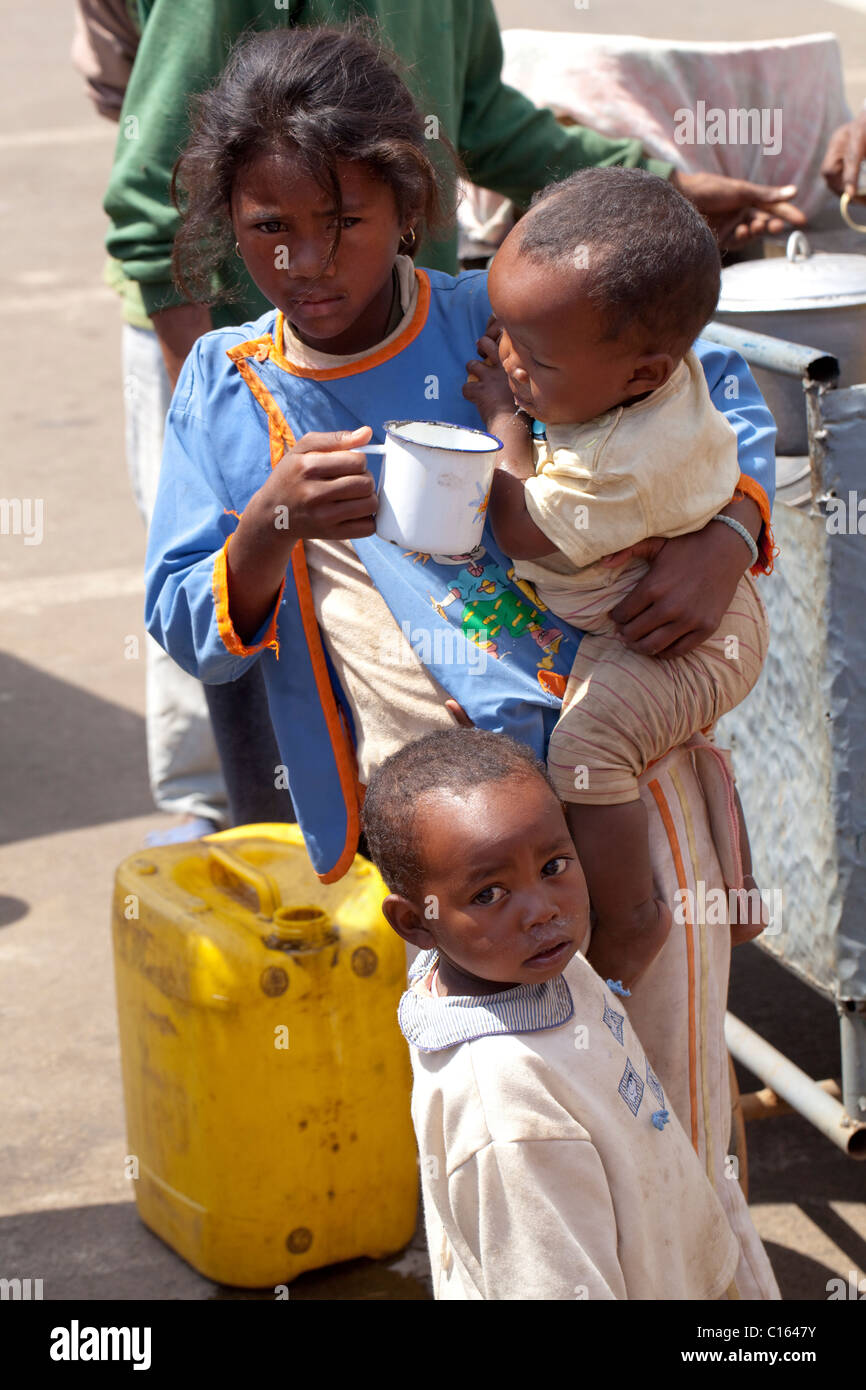 Girl having bought drinking water for sibling younger brothers. Toamasina or Tamatave. Atsinanana Region. Eastern Madagascar. Stock Photo
