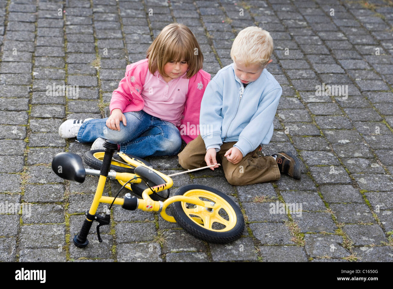 A boy, four years of age, explaining his balance bike to a girl, three