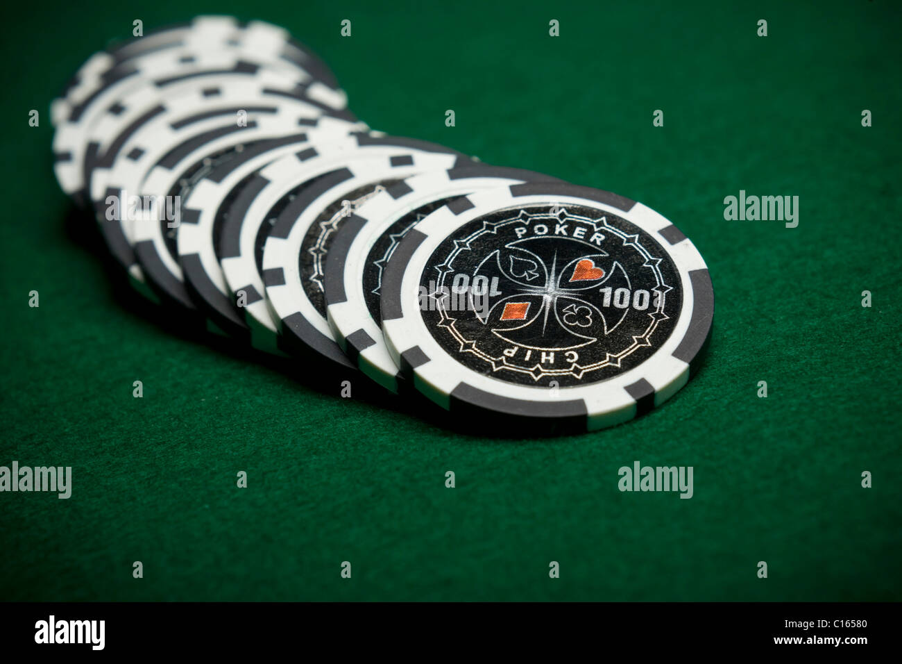 Black poker chips on green felt Stock Photo