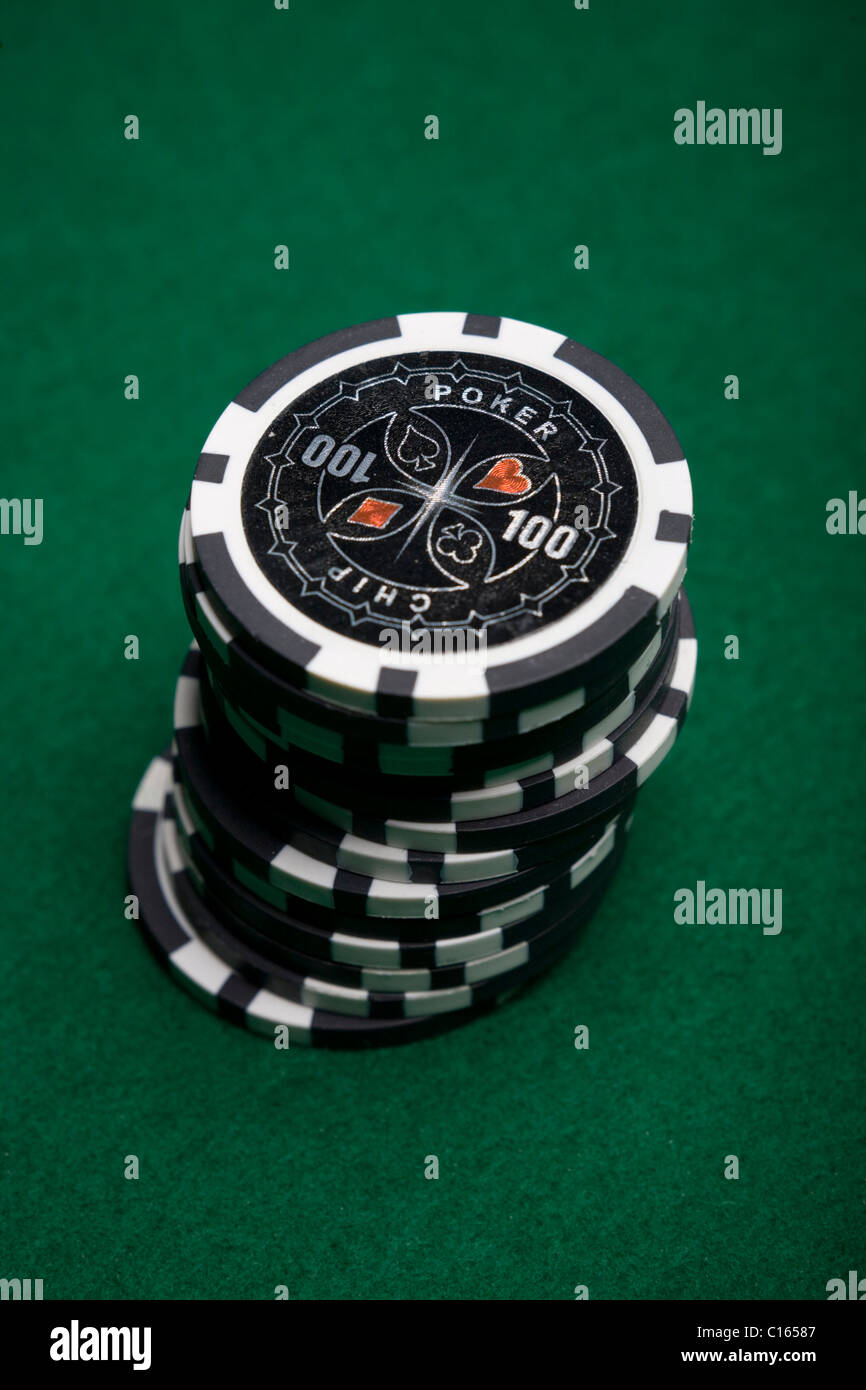 Stacked black poker chips on green felt Stock Photo