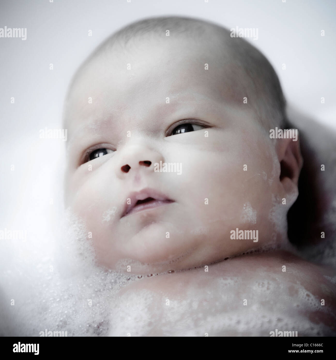 A newborn baby in a bubble bath head and shoulders Stock Photo