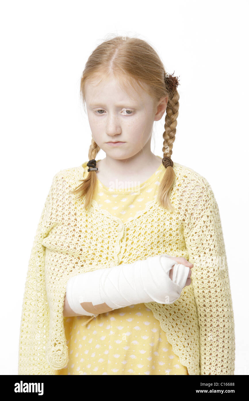 Girl, 8 years old, with braided hair and a broken arm in plaster looking sadly downwards Stock Photo
