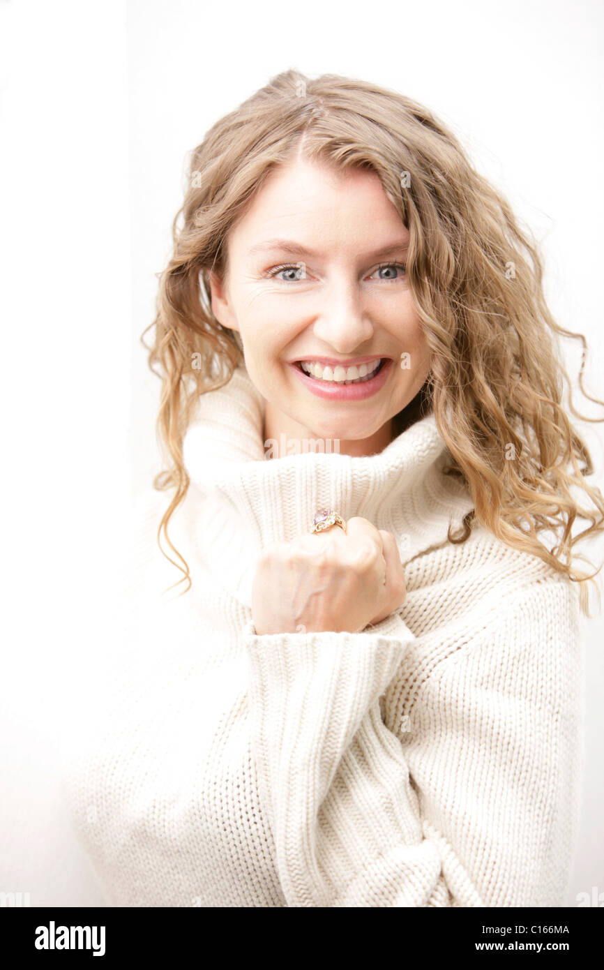 A blonde woman in a white pullover laughing and balling a fist Stock Photo