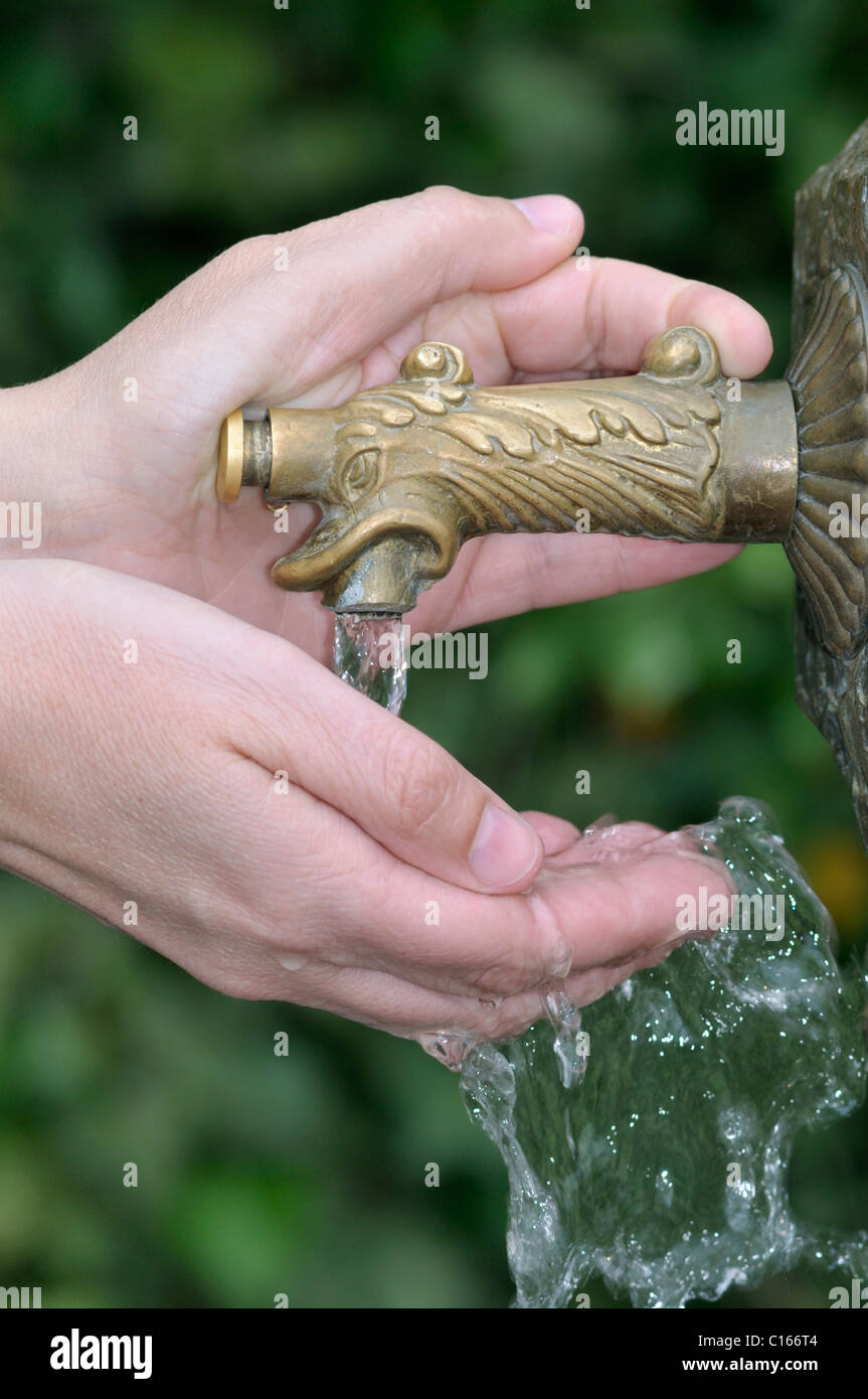 Hand pressing button on a bubbly water fountain Stock Photo