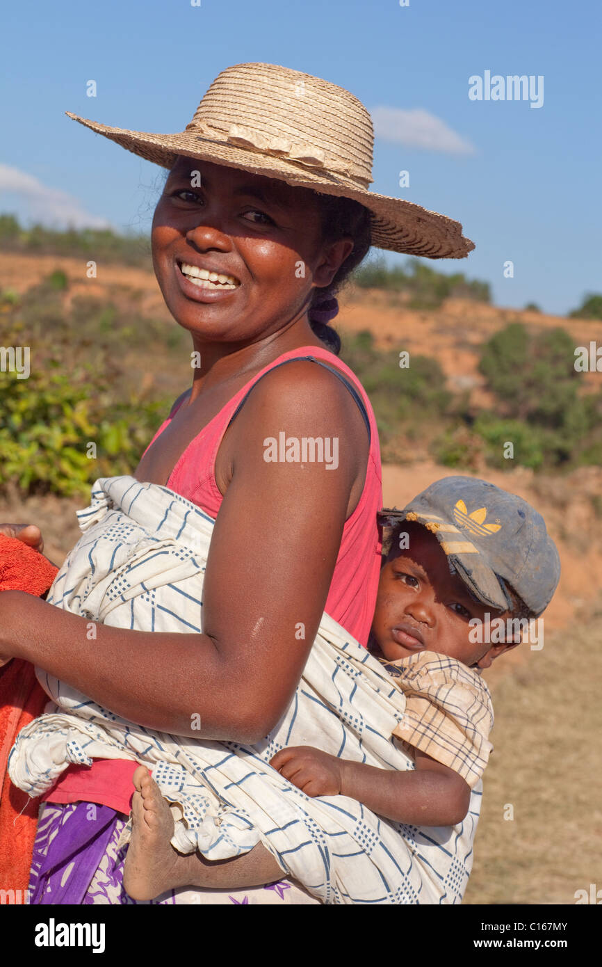 Mother carrying child slung on back from working in the fields. Near Fianarantsoa. Southern Madagascar. Stock Photo