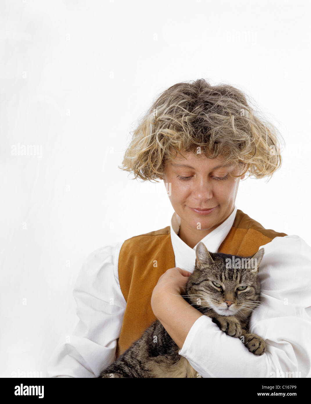 A blond woman is holding a tabby cat in her arms, the cat is purring with pleasure Stock Photo