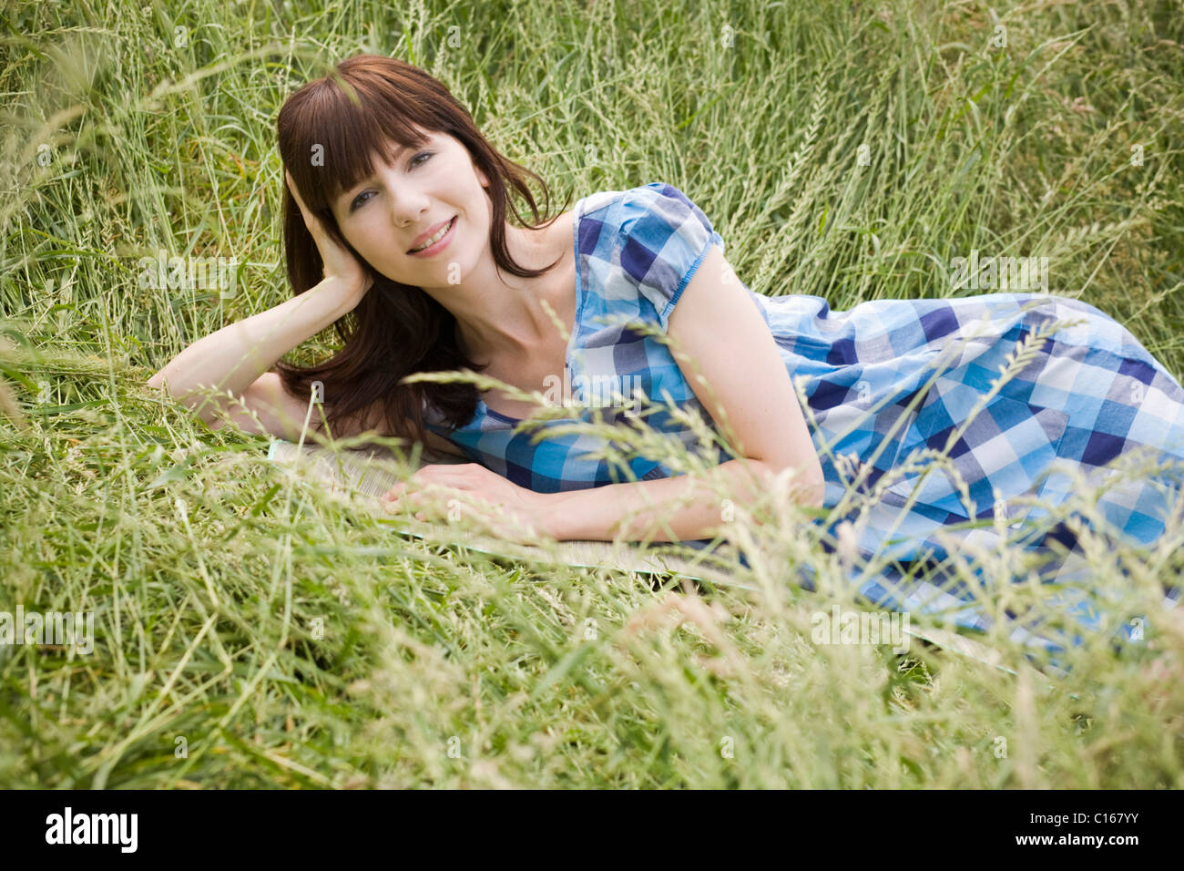 Young dark-haired woman lying in tall grass Stock Photo