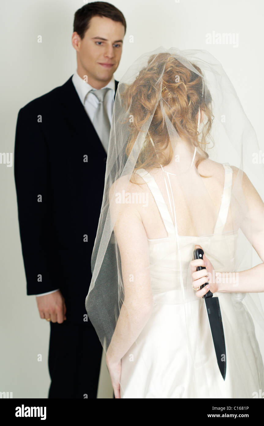 Bride and groom, bride hiding a knife behind her back Stock Photo