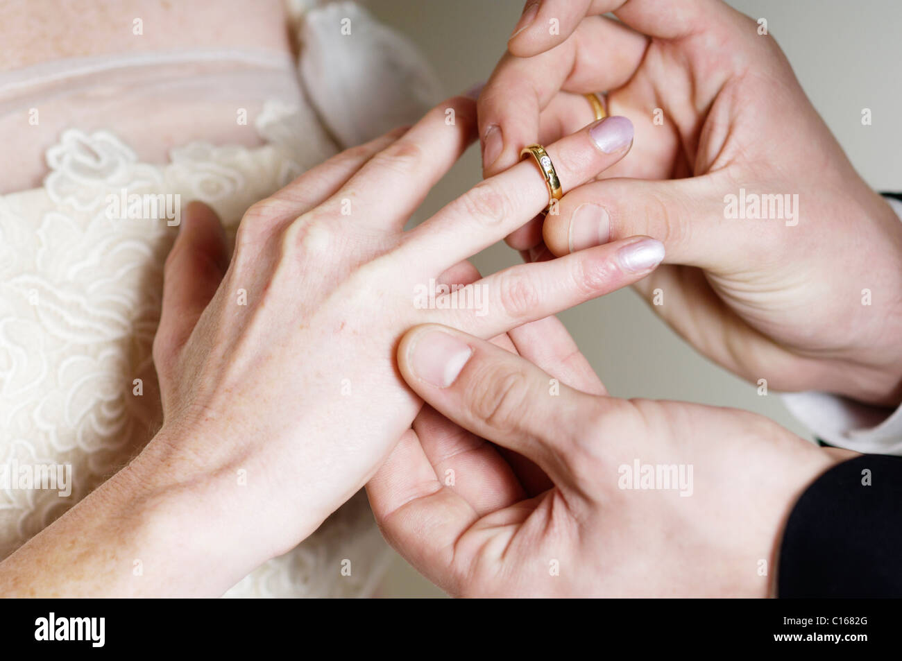 Groom placing the wedding ring on the bride's finger Stock Photo