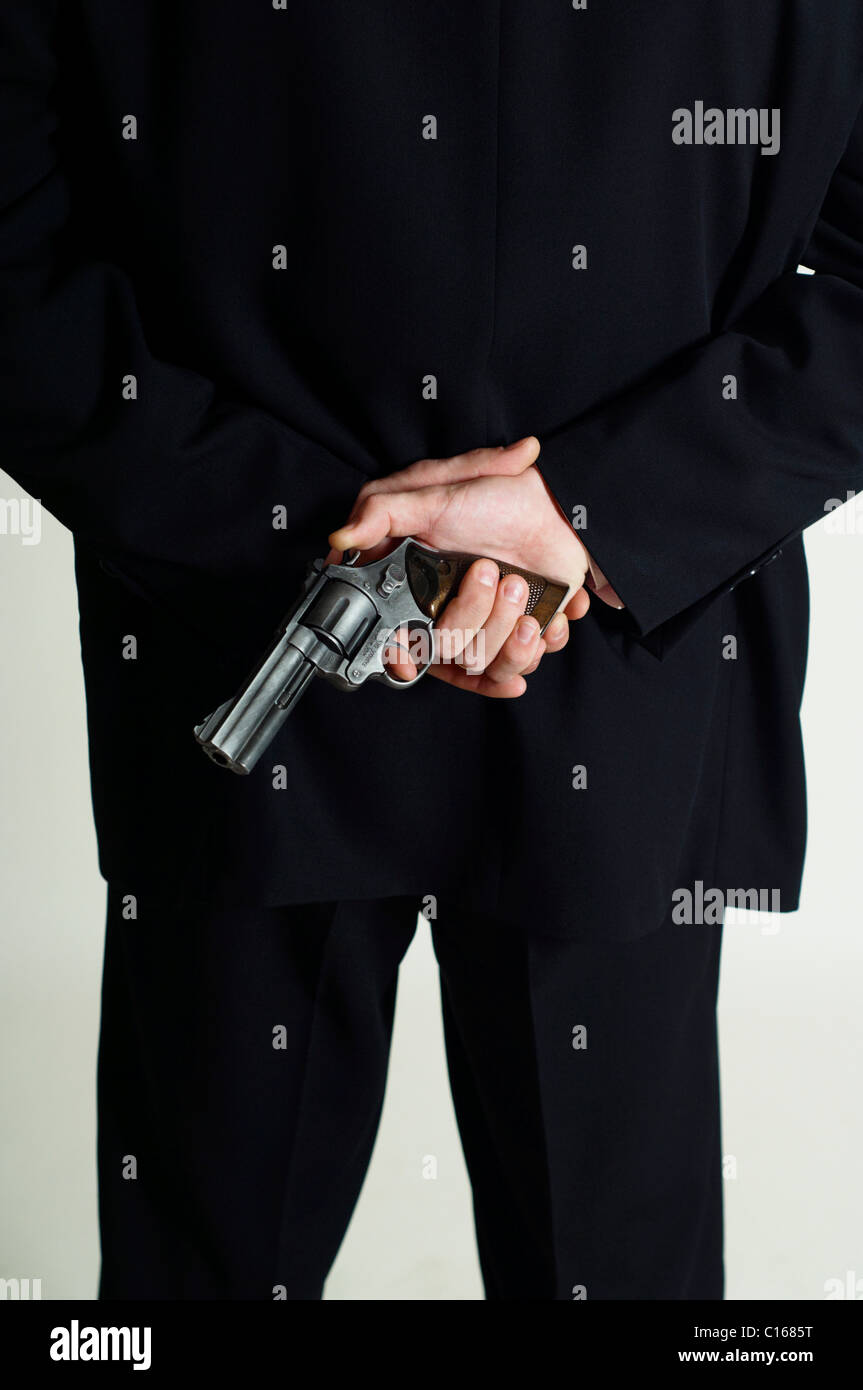 Man hiding a revolver behind his back Stock Photo