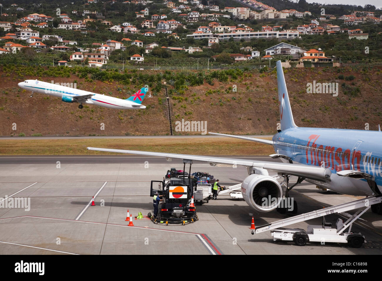 A First Choice aircraft takes off whilst a Thomson aircraft prepares for boarding at Funchal international airport, Madeira. Stock Photo