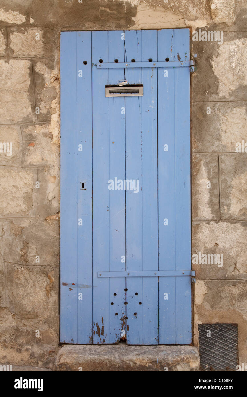 Traditional wooden door in faded blue paint, set in an ancient stone wall Stock Photo