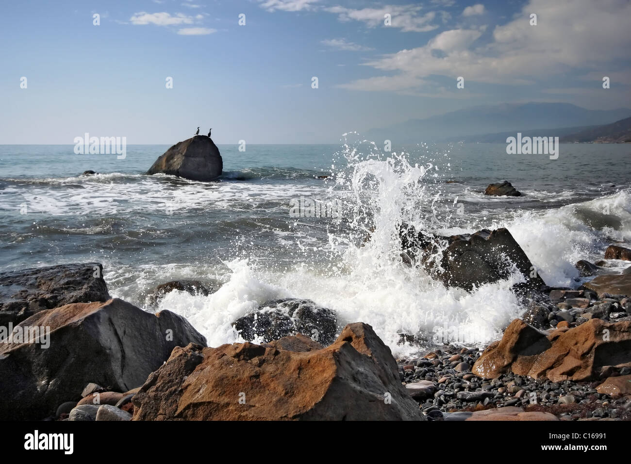 Coast of Black sea. Breaking waves and stones against a two divers. Crimea. Ukraine. Stock Photo