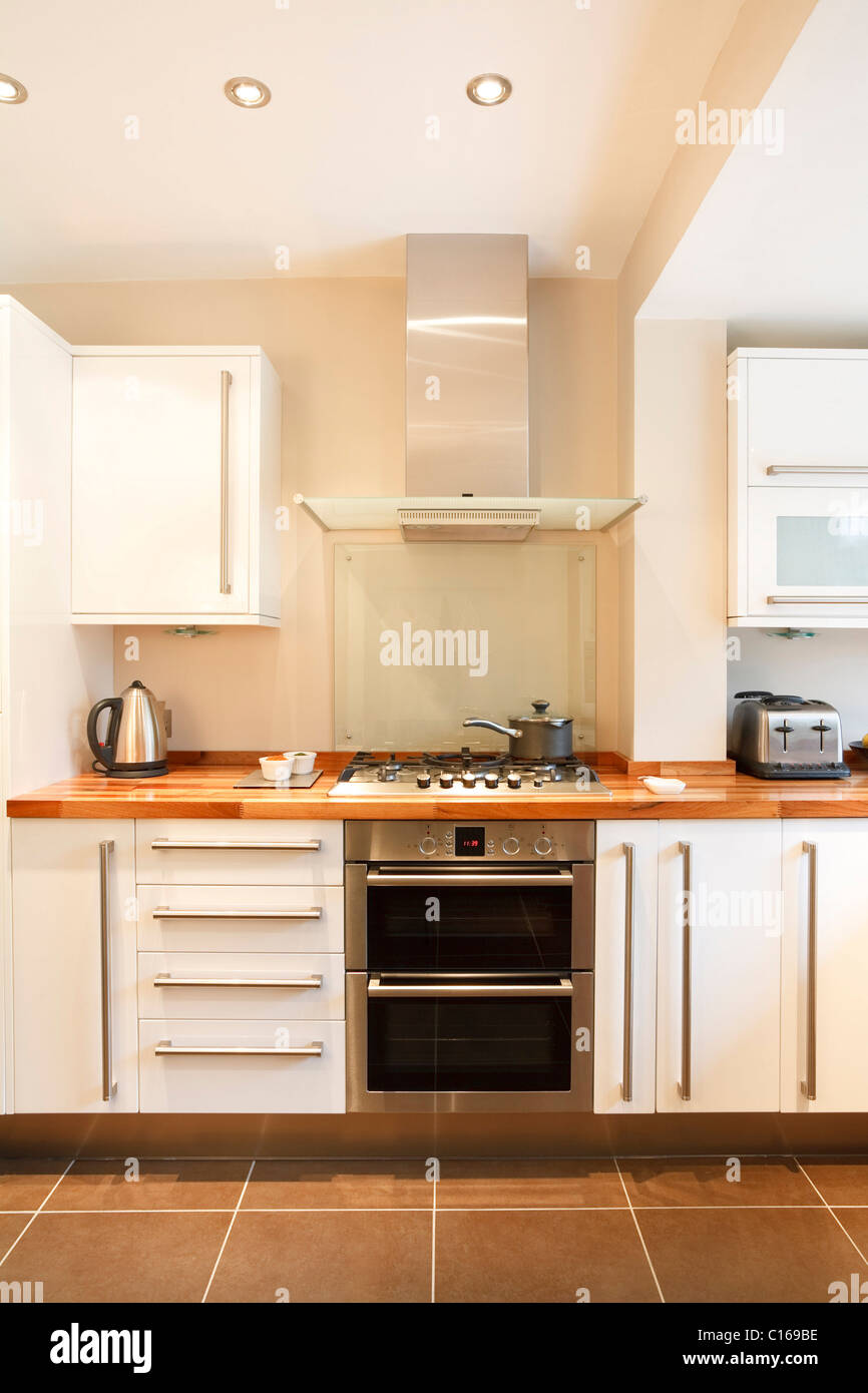 Modern white kitchen with wooden worktops and stainless steel appliances Stock Photo