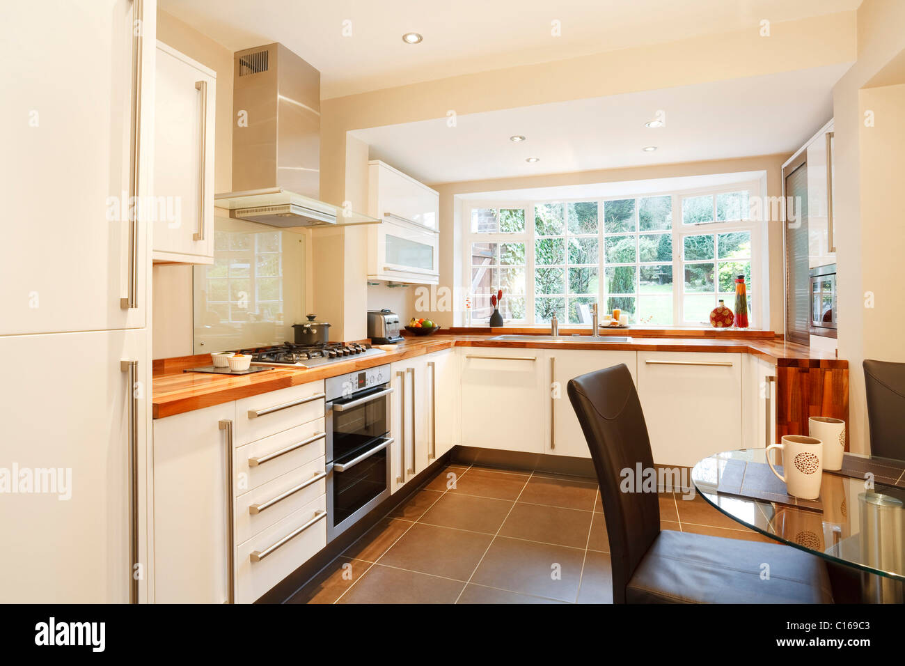 Contemporary designer kitchen and breakfast area with modern white units and stainless steel appliances Stock Photo