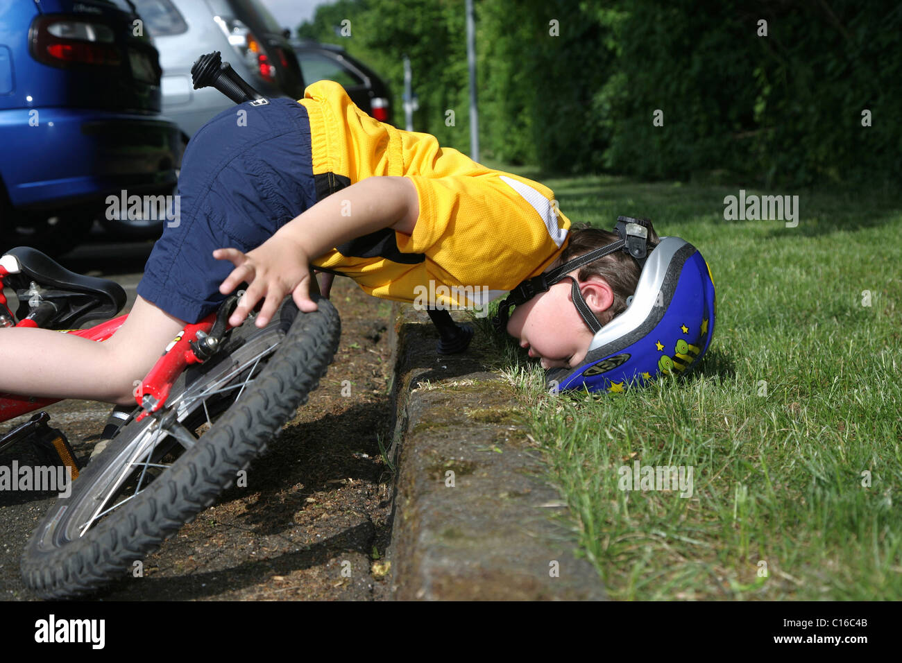 Fiveyearold boy wearing a bicycle helmet falling off his bicycle