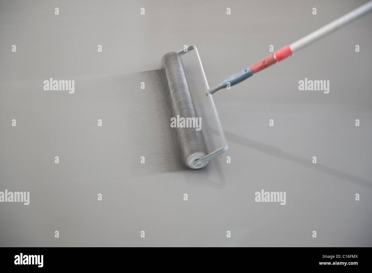 Concrete filler and a spiked roller spreading concrete on the ground