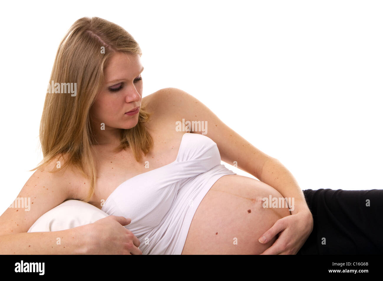 Pregnant woman in a reclining position thinking about her unborn child as she holds her abdomen. Stock Photo