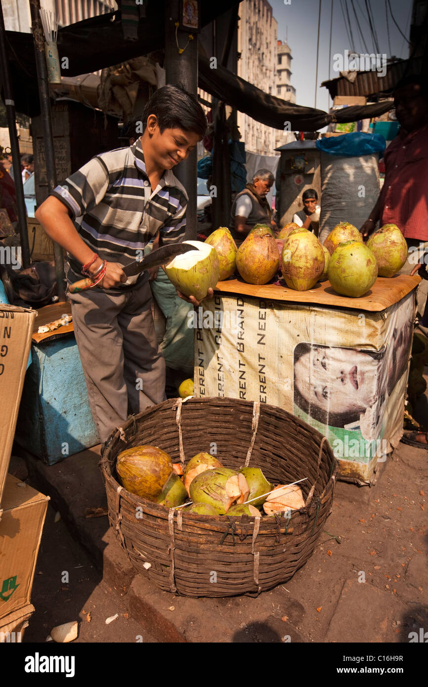 India, West Bengal, Kolkata, Barabazaar, young man opening young coconut at roadside stall Stock Photo