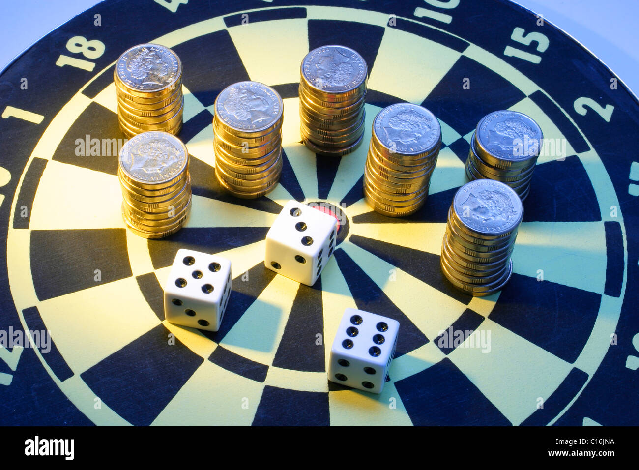 Coins and dice on dart board Stock Photo