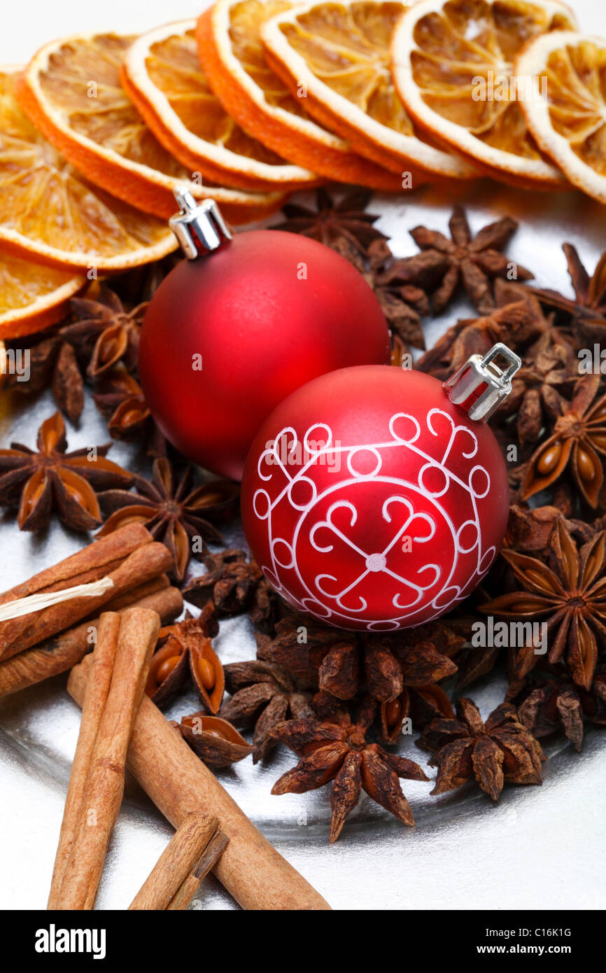 Christmas baubles, star anise, cinnamon sticks and dried slices of orange on a plate Stock Photo