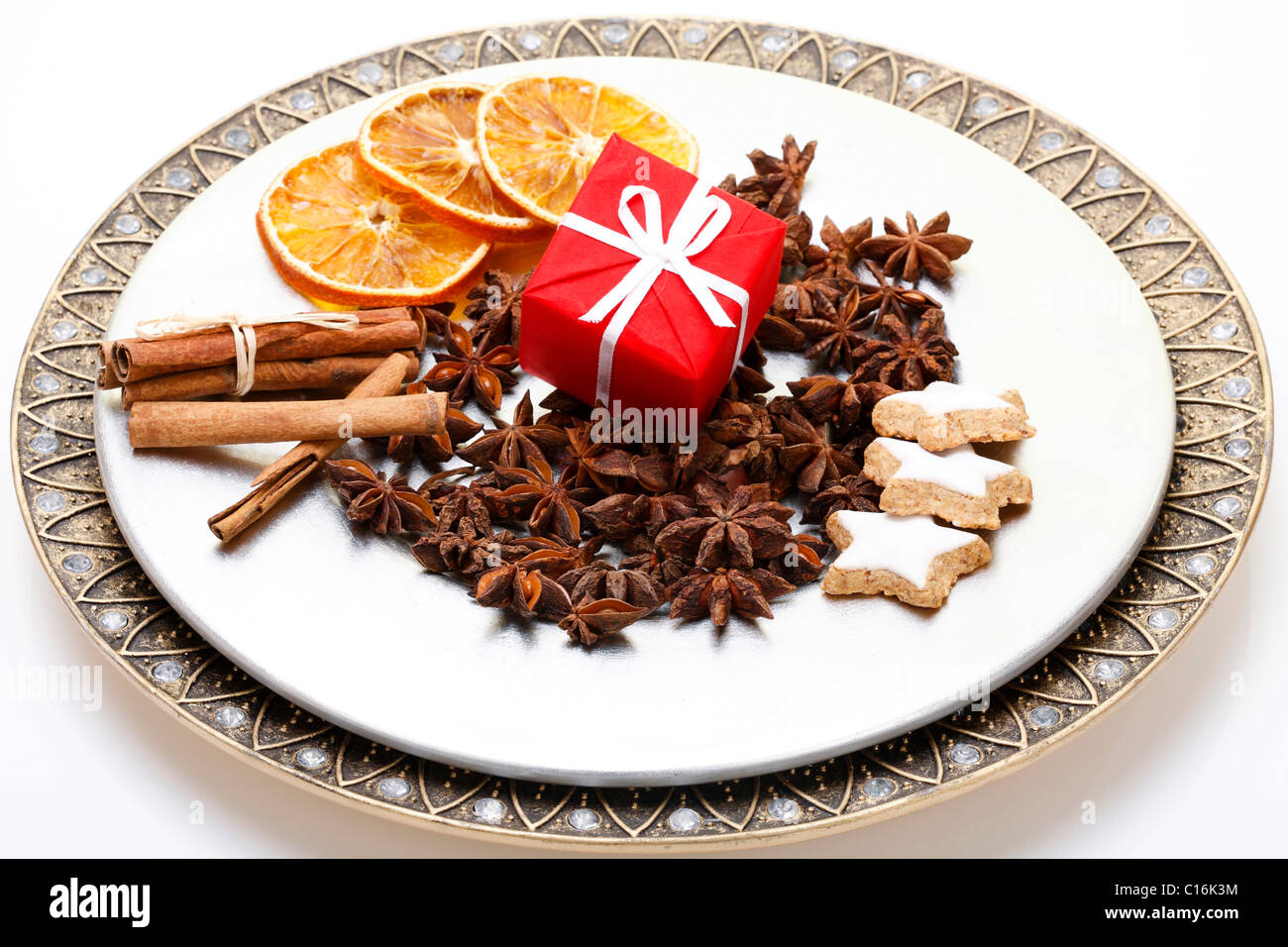 Christmas present, star anise, cinnamon sticks and dried slices of orange on a plate Stock Photo