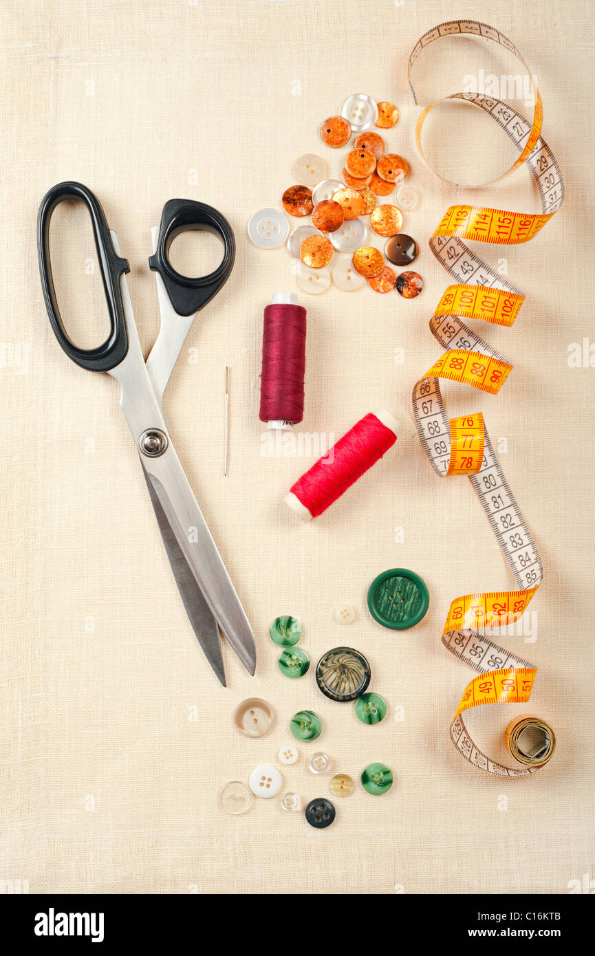 Sewing supplies. Set from measuring tape, buttons, bobbins of thread, needle and scissors on linen canvas Stock Photo