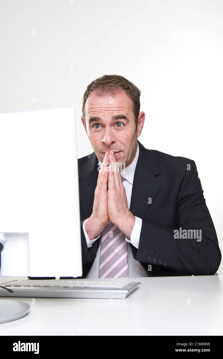 Businessmann sits praying in front of computer Stock Photo
