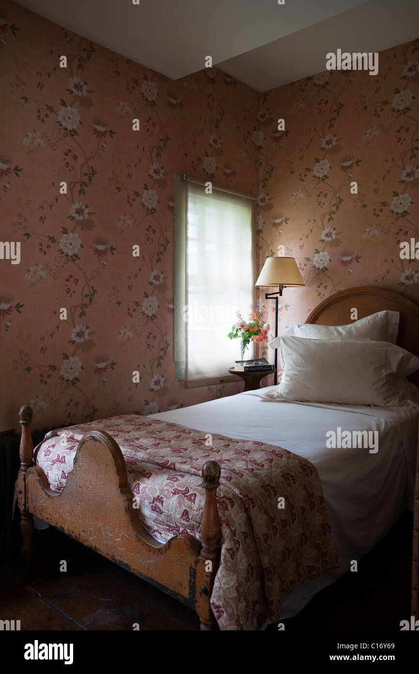 Single bed in 1830s Hudson Valley farmhouse bedroom with patterned wallpaper Stock Photo