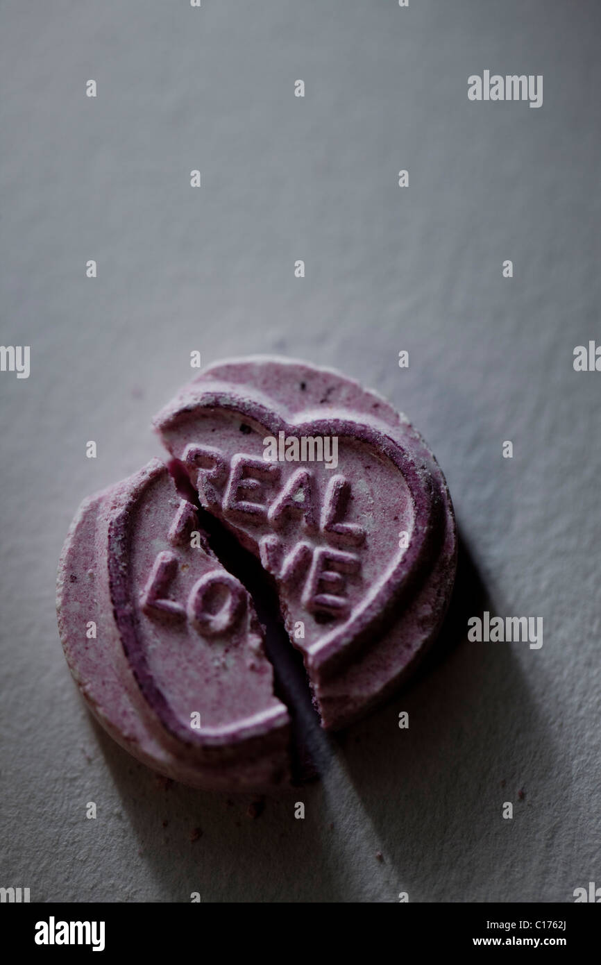 A broken love heart sweet with the message 'real love' Stock Photo