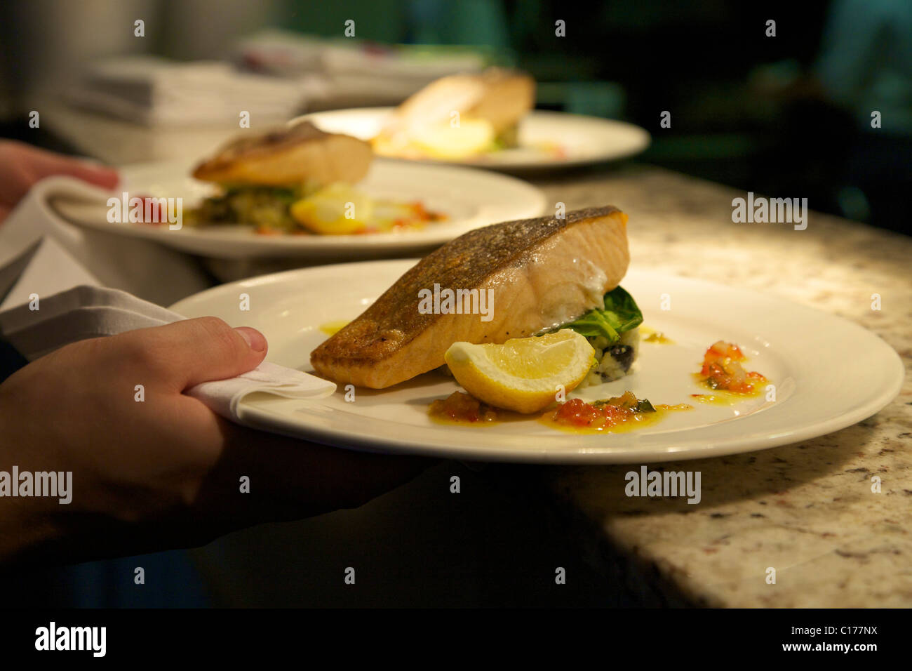 Dishes of salmon being taken from the kitchen a restaurant Stock Photo