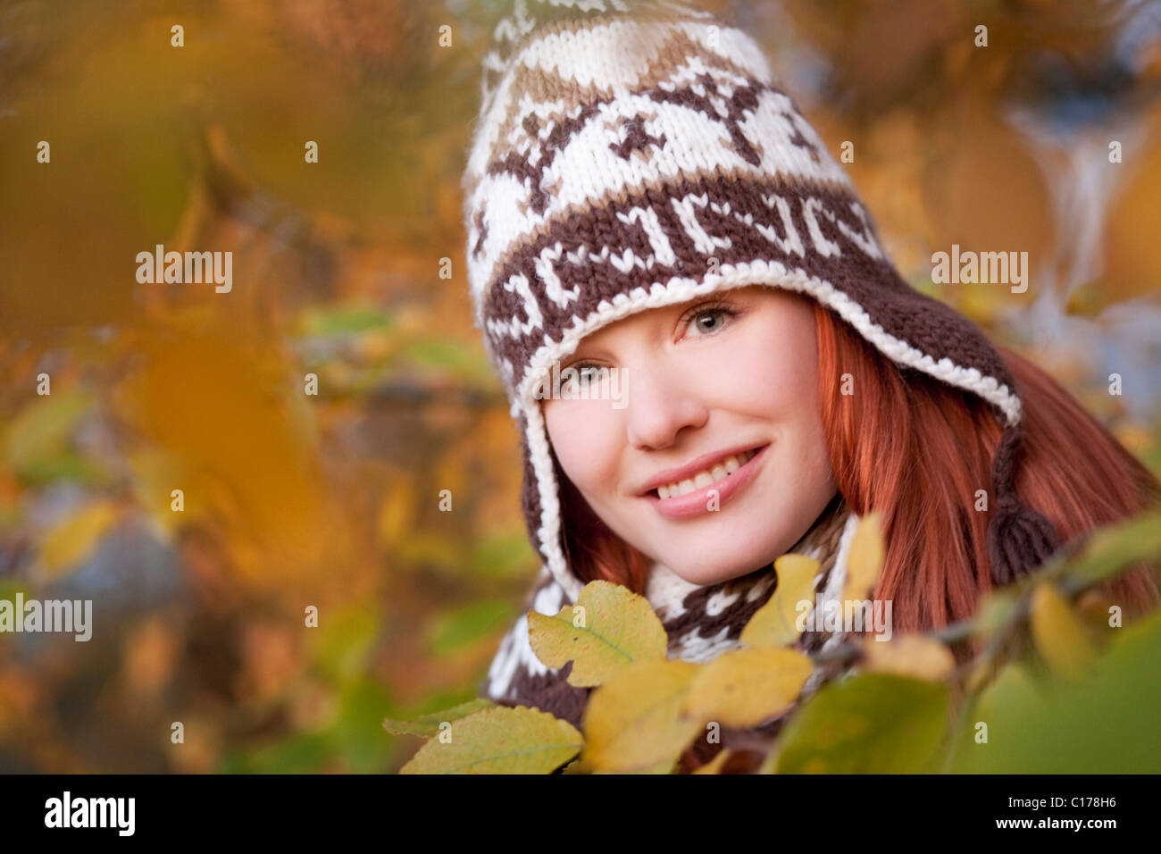 Young red haired woman wearing a woolen hat and scarf in an autumnal forest Stock Photo