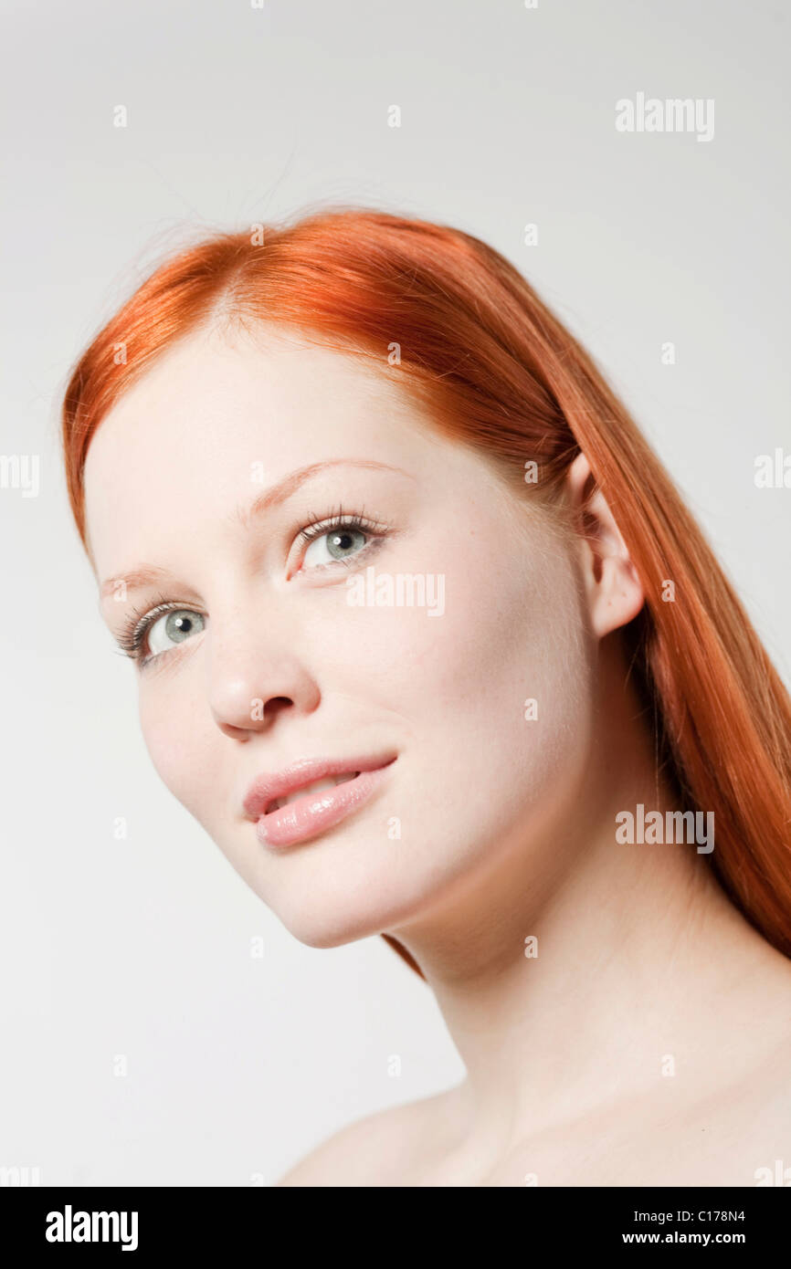 Portrait of a young red-haired woman in front of white backdrop Stock Photo