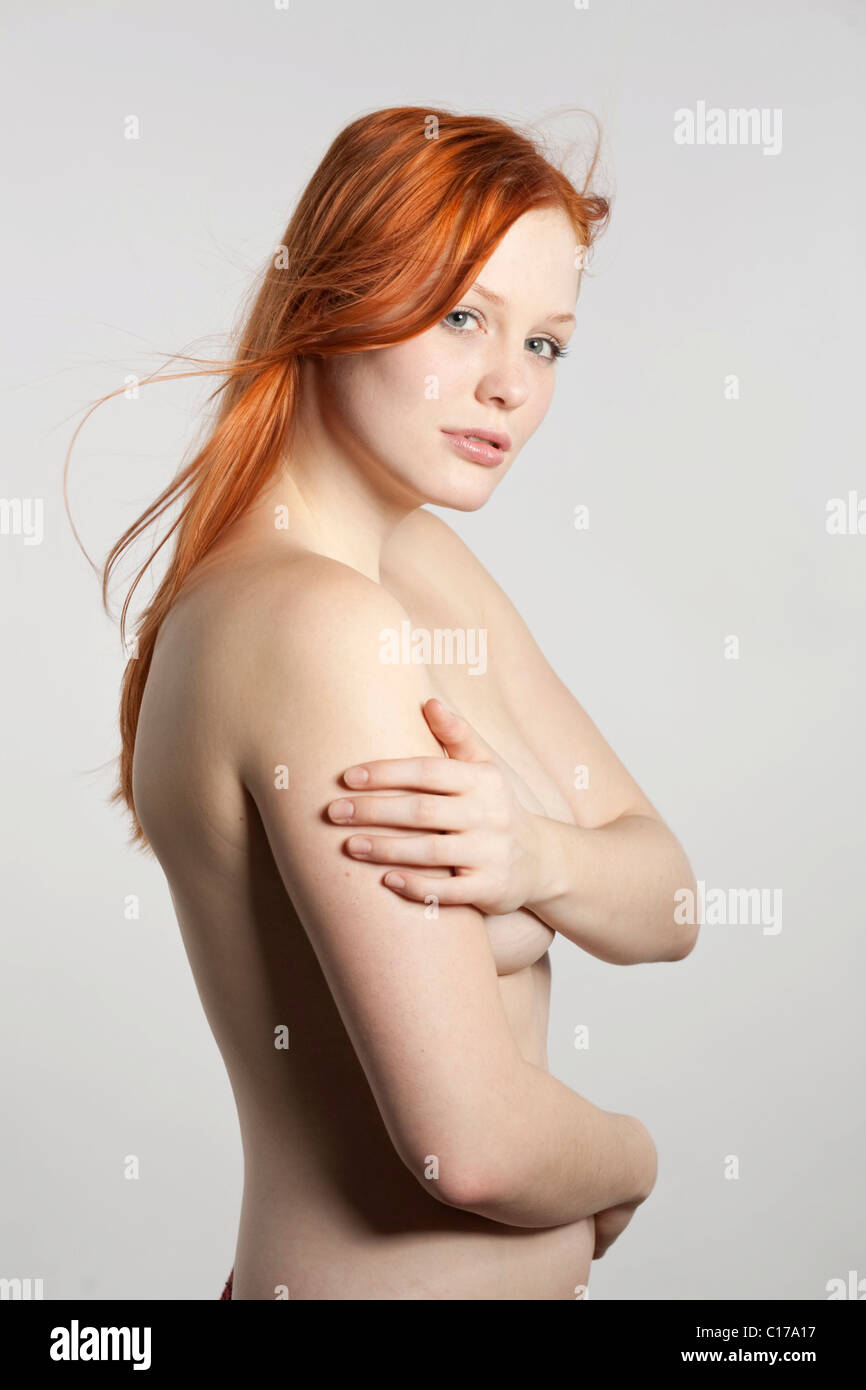Young red-haired woman with bare upper body in front of white backdrop Stock Photo