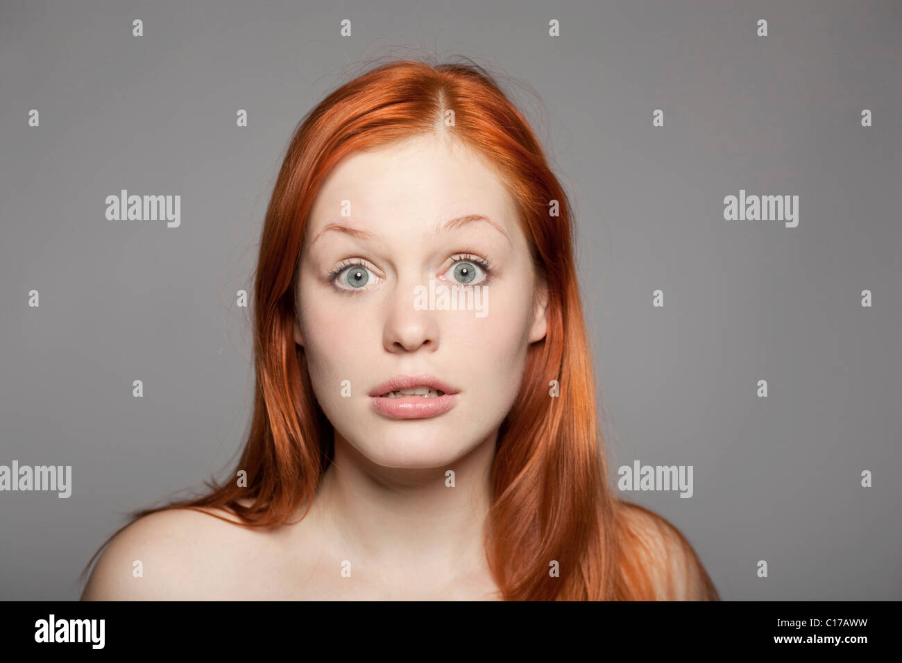 Surprised, young, red-haired woman looking into the camera Stock Photo