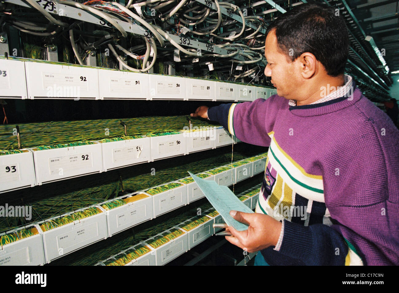 A IT technician works on wiring in a telecommunications digital ...
