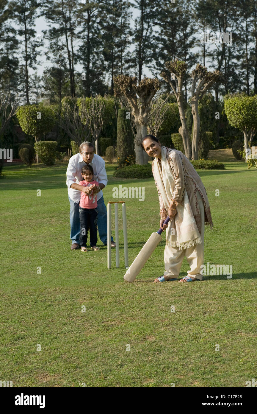 Family playing cricket in lawn Stock Photo